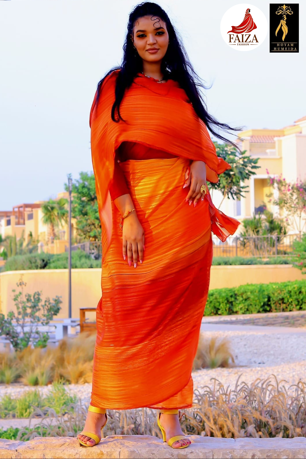 Woman in an orange sudanese toub standing outdoors with a blurred background