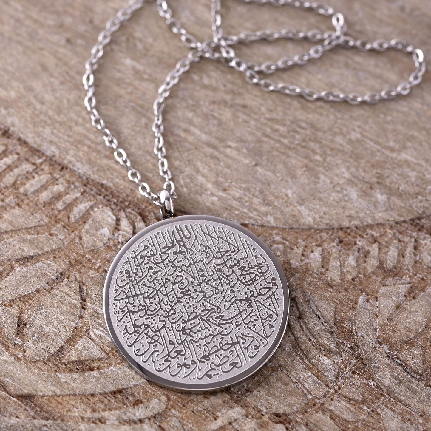 Silver necklace with a round pendant with arabic text, Ayat al kursi.