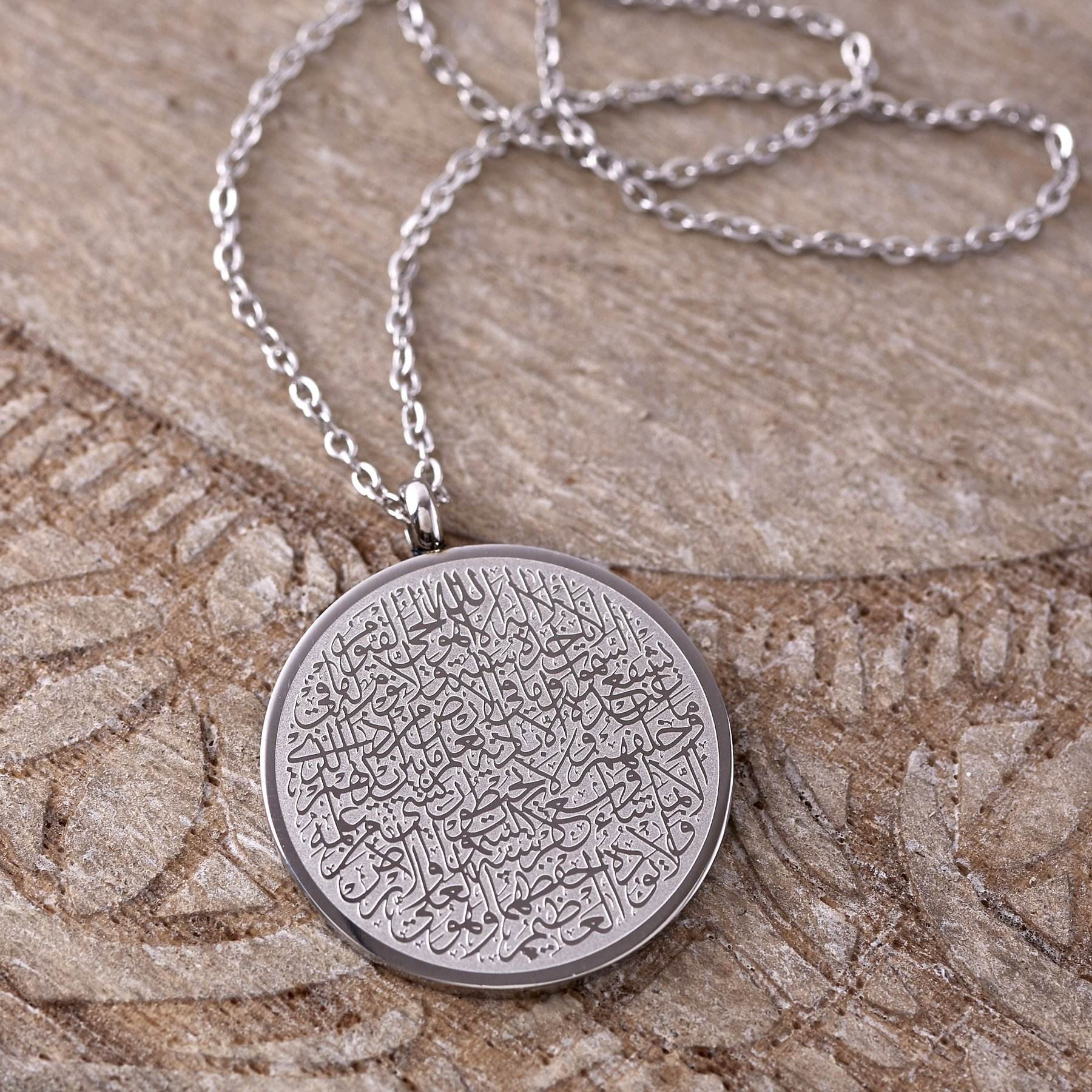 Silver necklace with a round pendant with arabic text, Ayat al kursi.