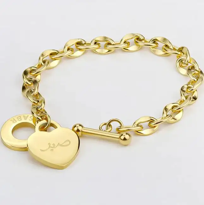 Gold chain bracelet with a heart padlock charm on a white background