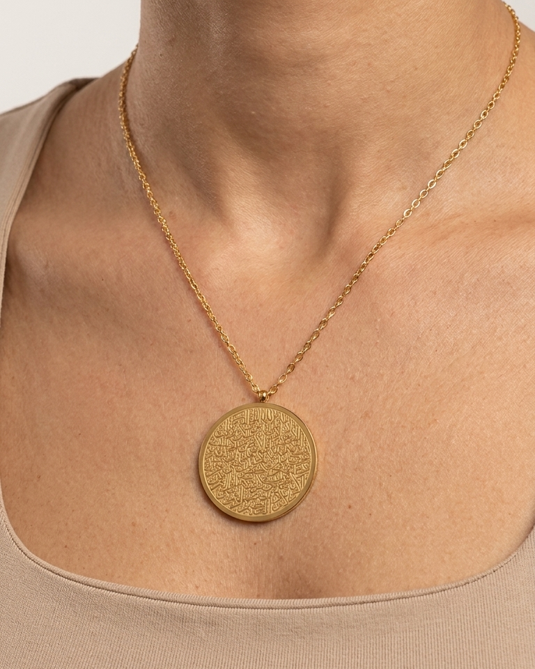 Gold necklace with a round pendant on a neutral background
