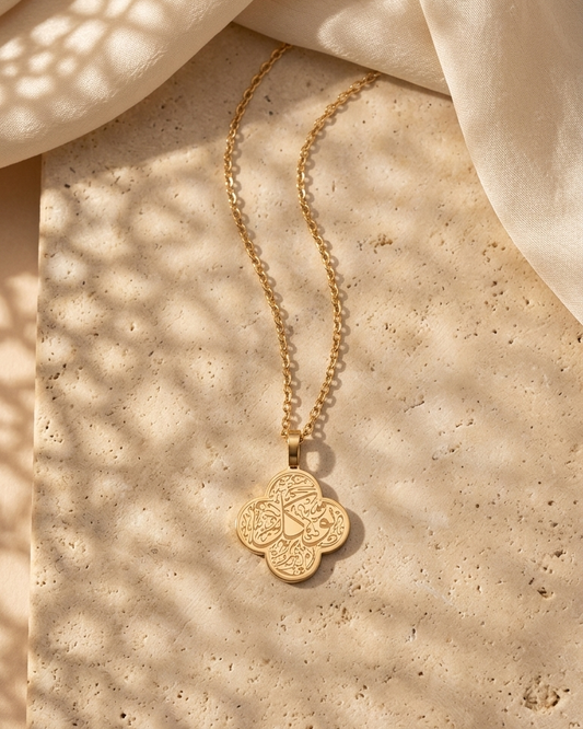 Gold necklace with a pendant on a beige textured surface